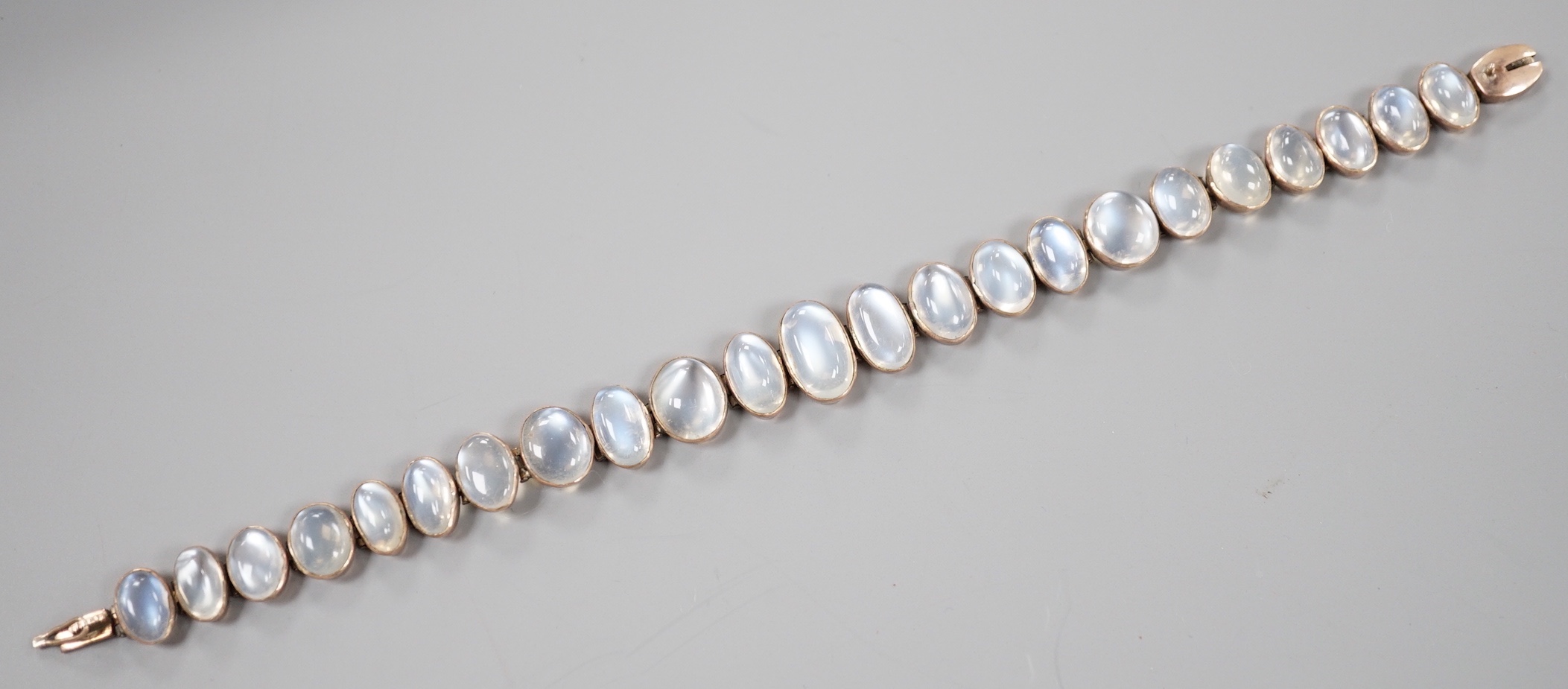 An Edwardian white and yellow metal, graduating oval cabochon moonstone set bracelet, 18cm, gross weight 14.6 grams.